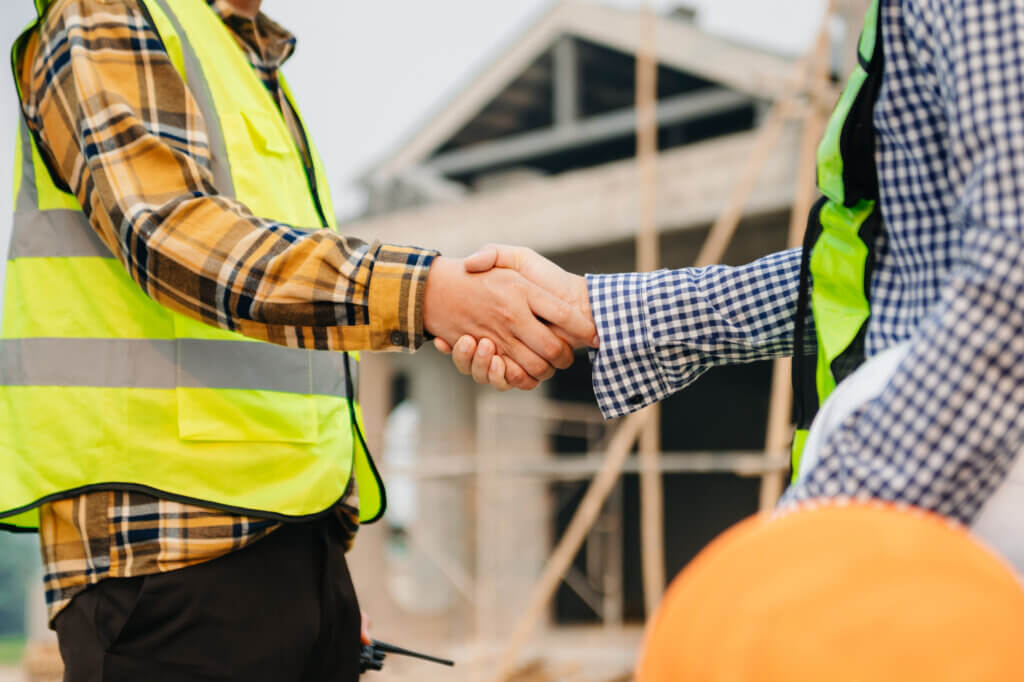 General contractor and subcontractor shaking hands on a Texas construction site